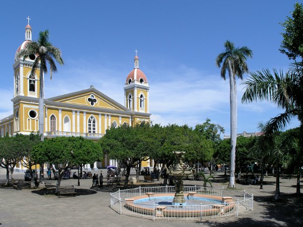 Fuente en una plaza arbolada con iglesia al fondo en Granada, Nicaragua